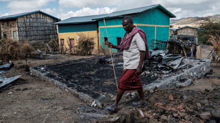 Addis Ceesay, 49, walks past his destroyed home in the village of Besoper, in the Tigray region of Ethiopia, December 9, 2020